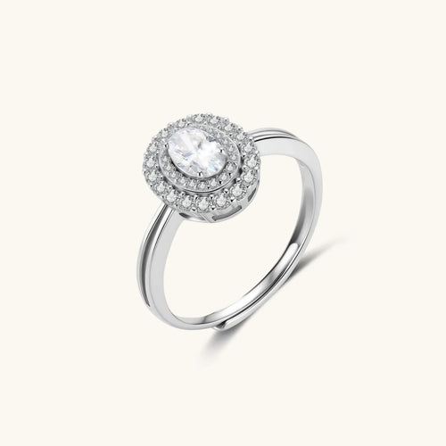 Sterling silver ring with oval moissanite center stone surrounded by double halo of sparkling stones on neutral background.